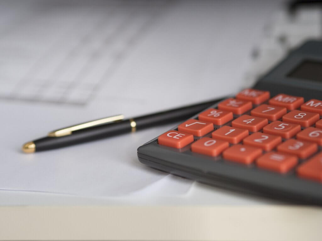  A calculator and pen that are used to calculate the cost of hiring a reliable SEO company