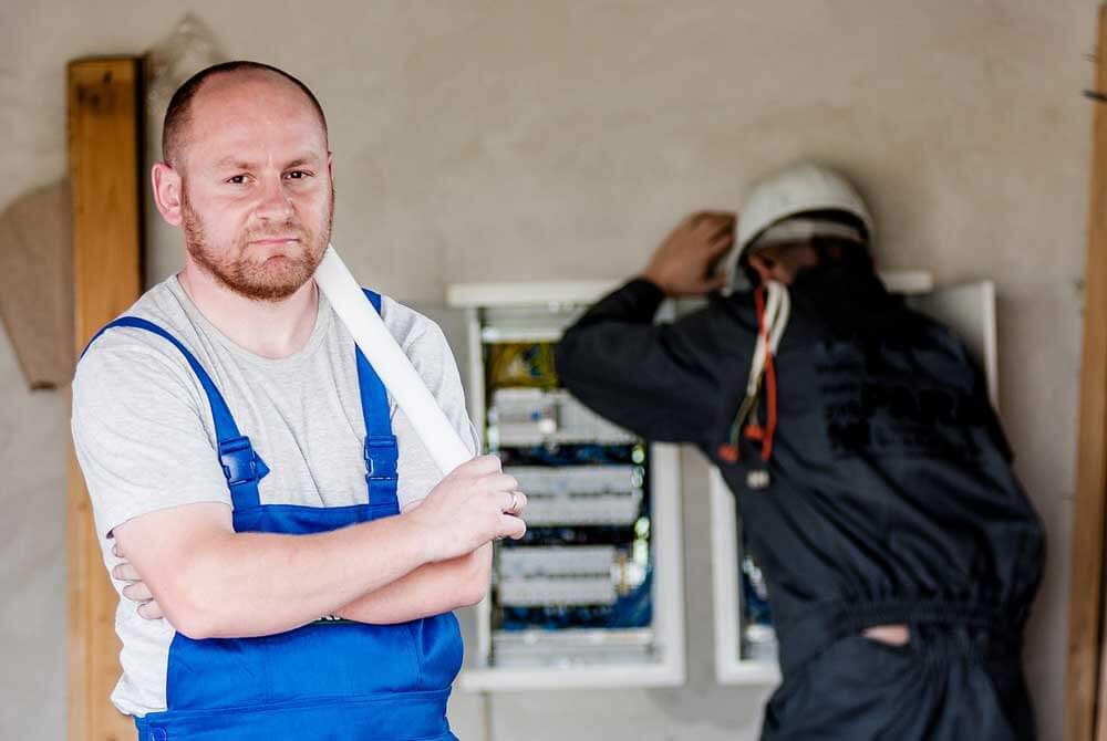 An electrician taking a break while his work partner continues working.